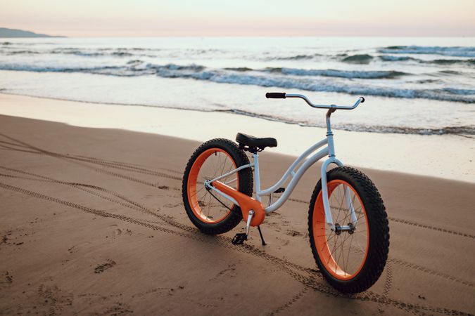 Modern fat bicycle parked at beach on sunset