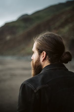 Bearded traveler looking away near sea