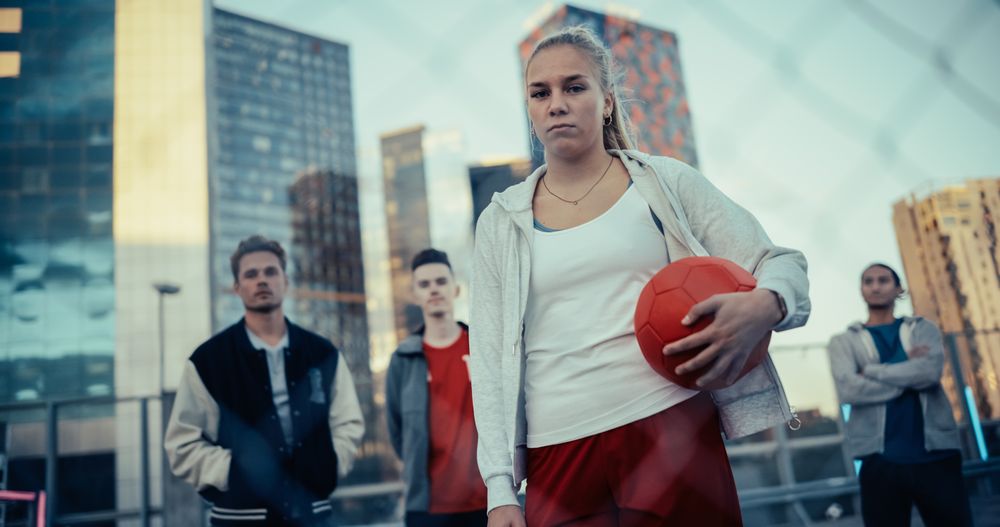 Empowering Portrait of a Sporty Young Woman Looking at Camera, Holding a Red Soccer Ball in Her Hands.