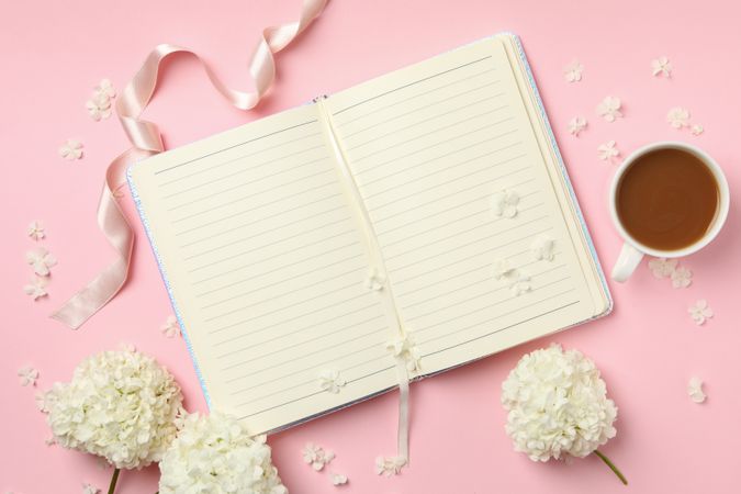 Notebook, coffee and hydrangea flowers on pink background