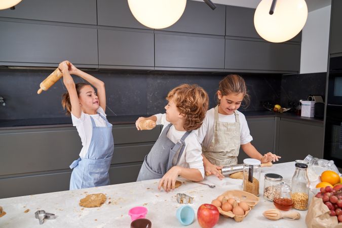 Children fooling around while baking at kitchen