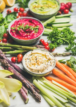 Fresh colorful vegetables and dips with hummus, avocados, asparagus, carrots, close up