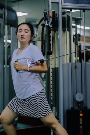 An Asian woman uses a machine at a gym.