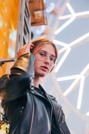 Serious woman standing at dusk near lit Ferris wheel