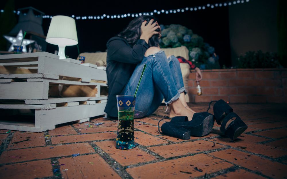 Inebriated young woman sitting around after party with her shoes off