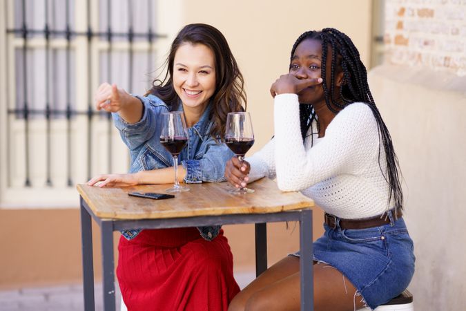 Woman pointing something out to her friend beside her at wine bar