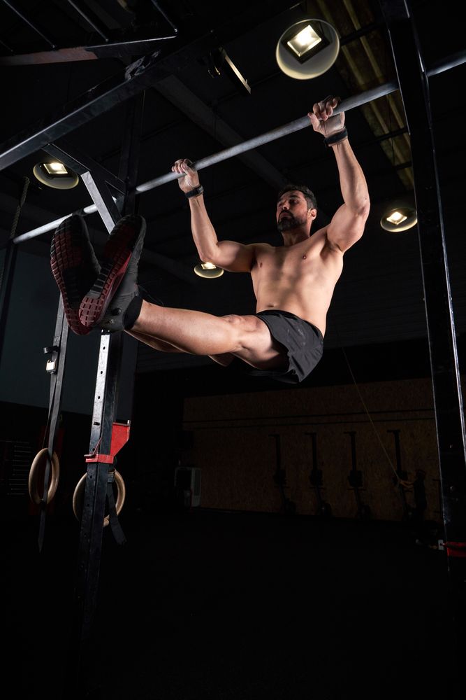 Shirtless gymnast doing exercise on bar