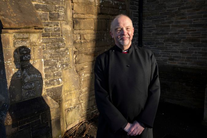 Vicar standing outside church in sun