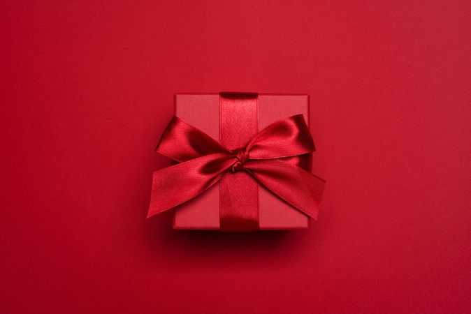 Red present with red bow on red background