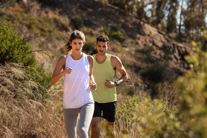Healthy young couple running on mountain trail