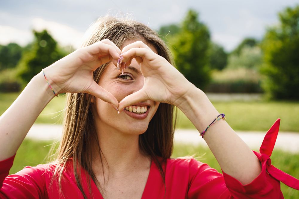 Portrait of a woman watching through the hearth shape made with her hands