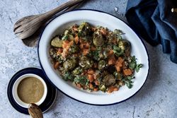 Braised brussels sprouts and pumpkin with quinoa in bowl near cup of sauce