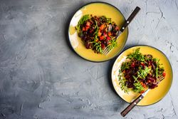Top view of two beet salads served on yellow plates with space for text