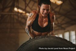 Strong woman performing tire flipping workout 5wp714