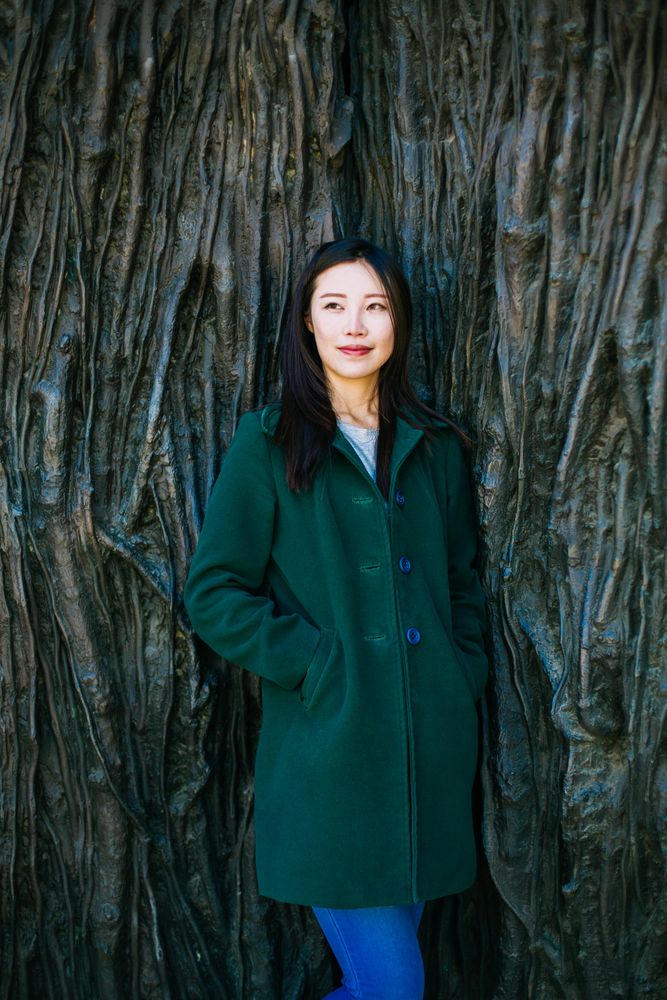 Pensive Asian woman leaning on rough wall