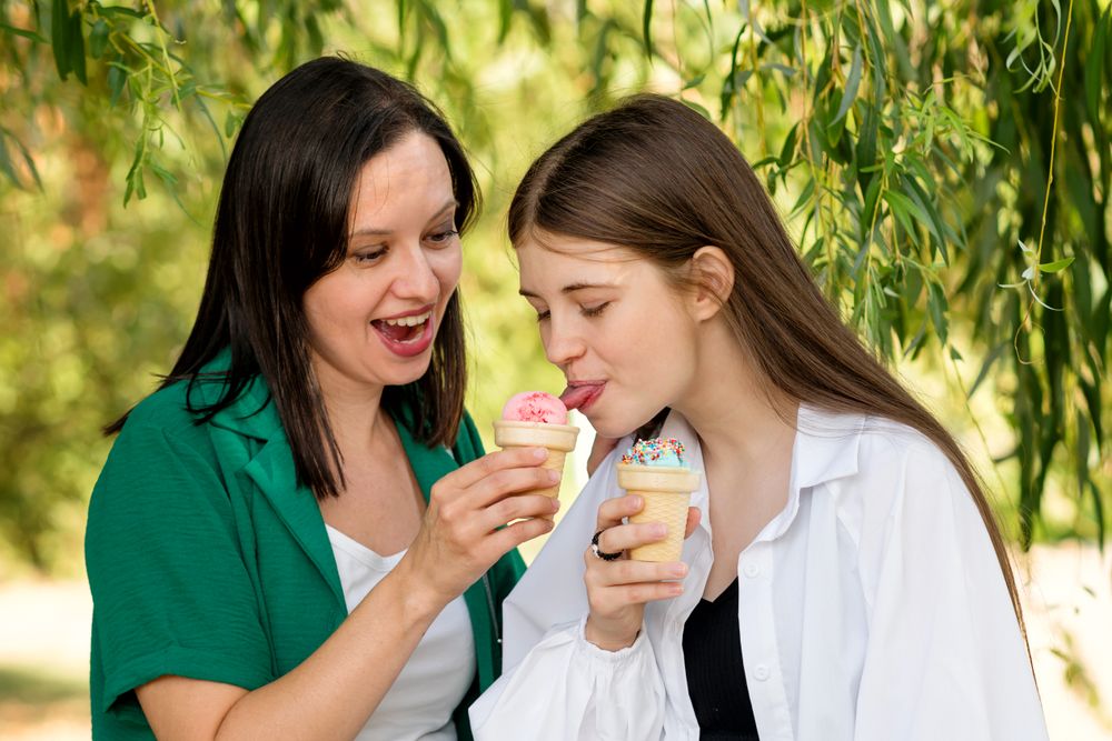 Mom and teenage daughter eat ice cream on walk