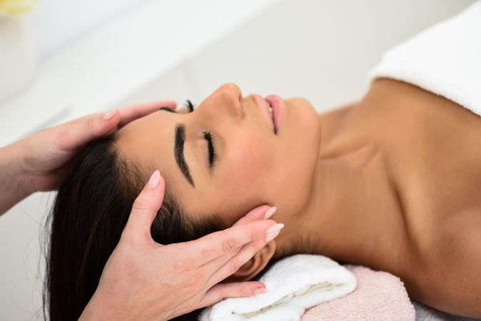 Woman having relaxing forehead massage in spa wellness center