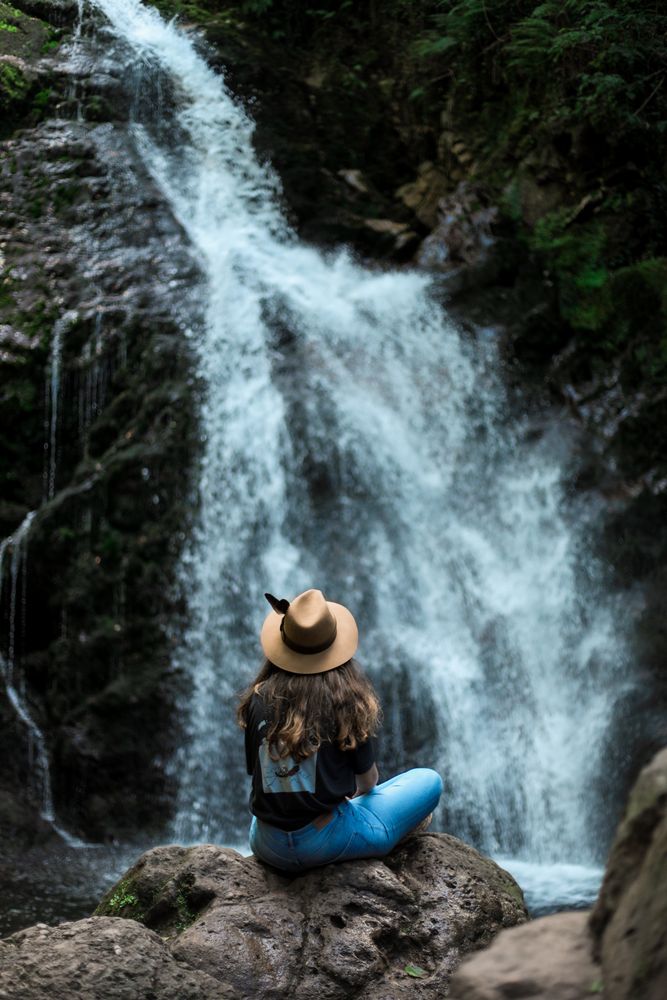 Smiling woman sitting near waterfall