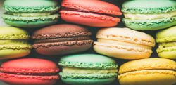 Bright multi-colored macaron pastries tightly stacked, side view, wide composition, close up