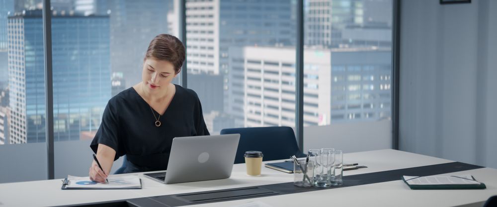 Portrait of Successful Businesswoman Working on Laptop Computer in Her Big City Corner Office.