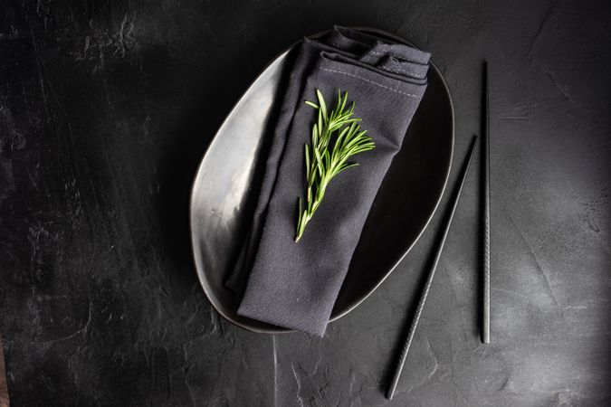 Minimalistic table setting in dark color with rosemary sprig and copy space
