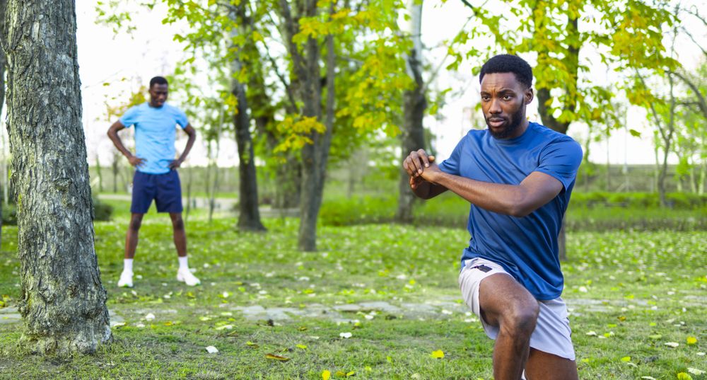 Group Fitness Class Outdoors in Nature with Trainer Encouraging Balance and Focus