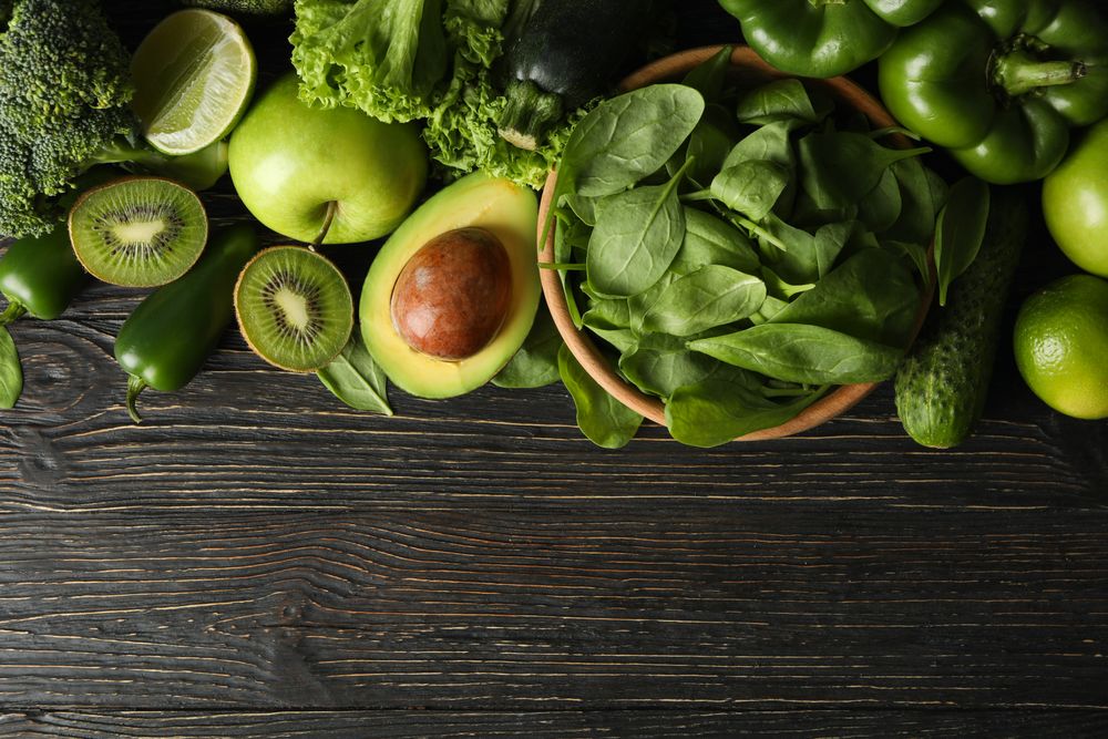 Green vegetables and fruits on wooden background
