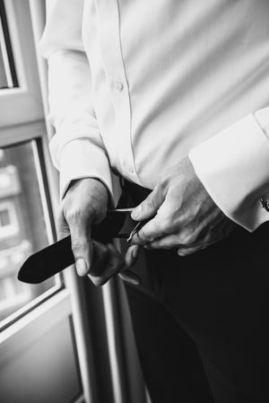 Man buttoning belt on pants