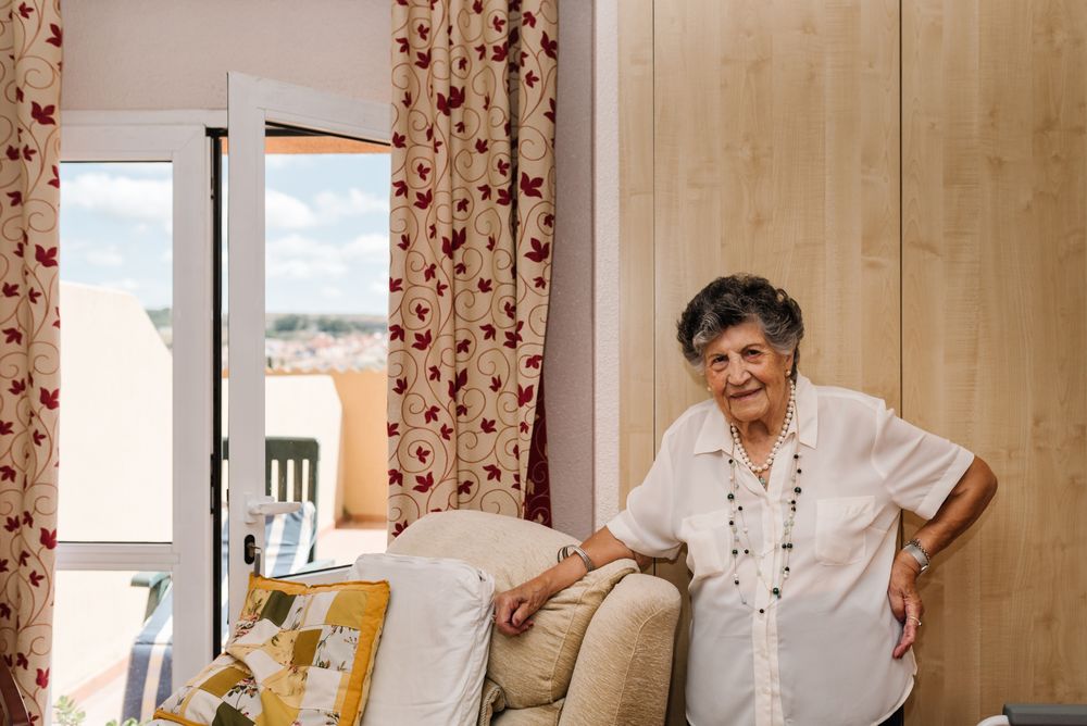 Older woman standing near armchair at home