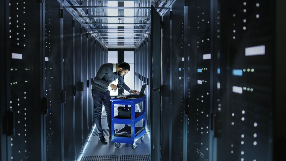 IT Engineer Works on a Laptop and Scans Hard Drives That are Lying on a Crash Cart.