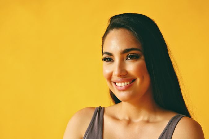 Smiling Hispanic woman looking away from camera in yellow room