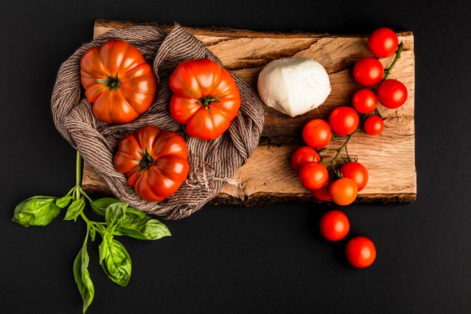 Tomatoes, mozzarella and napkin on wooden board