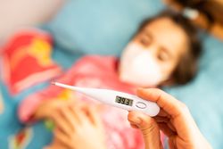 Digital thermometer reading 39.3 with little girl in the background