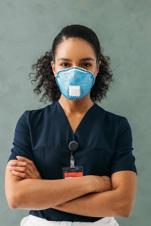 Black female medical worker in dark scrubs and protective face mask