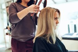 Close up of a woman sitting at a hair salon and getting her hair styled