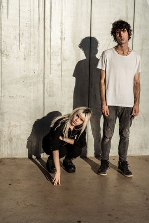 Rebellious trendy confident woman and calm guy against gray wall