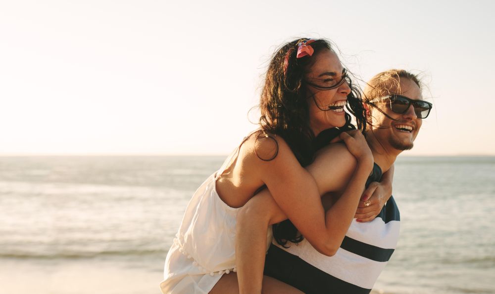 Free Photo  Man giving piggyback ride to woman on the beach