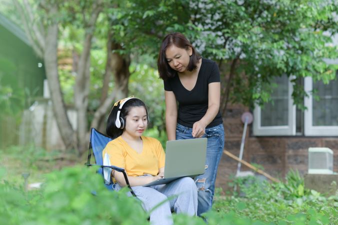 Two women working with the laptop from the home garden