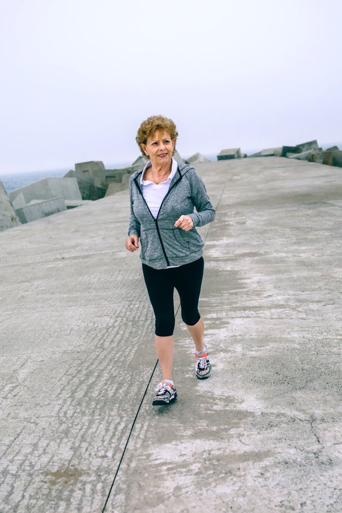Older sportswoman walking by sea pier
