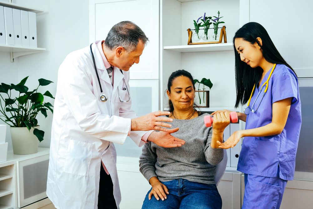 Doctor and physiotherapist helping patient with arm rehab exercises