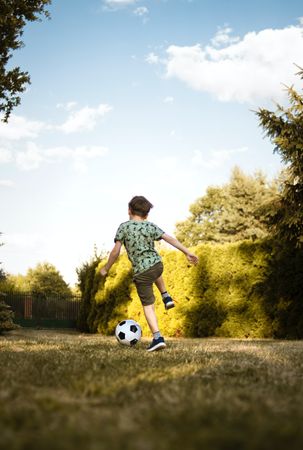 Back view of boy playing soccer in a park