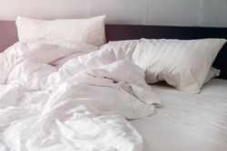 bed and pillows with wrinkle blanket in bedroom, from sleeping in a long night.