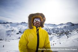 Man in yellow parka and goggles spending a winter day at a ski resort 4BLkd0