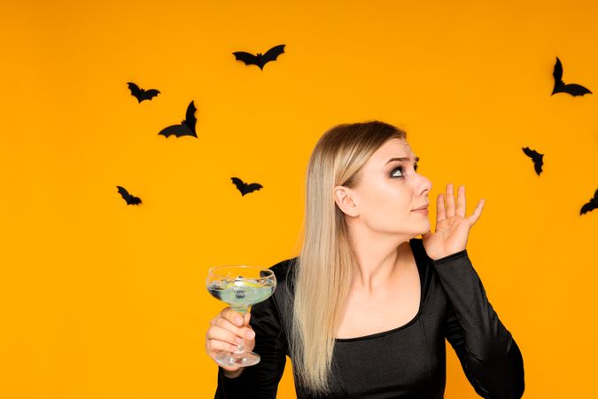 A woman at a party in the style of Halloween with a cocktail in her hands
