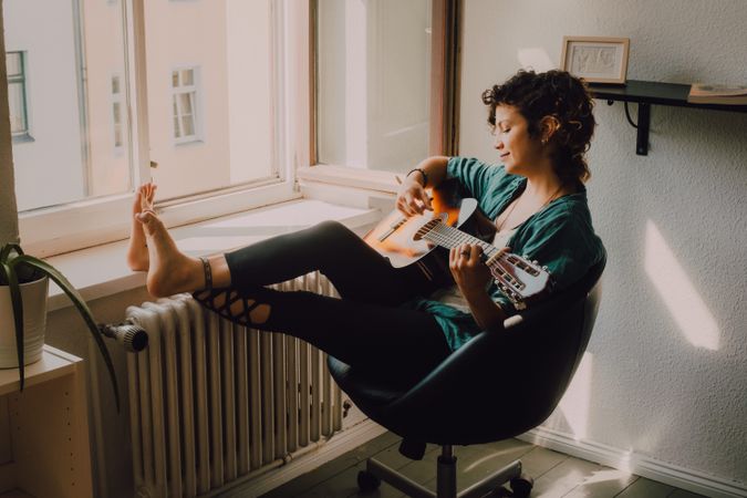 Content woman playing guitar at home