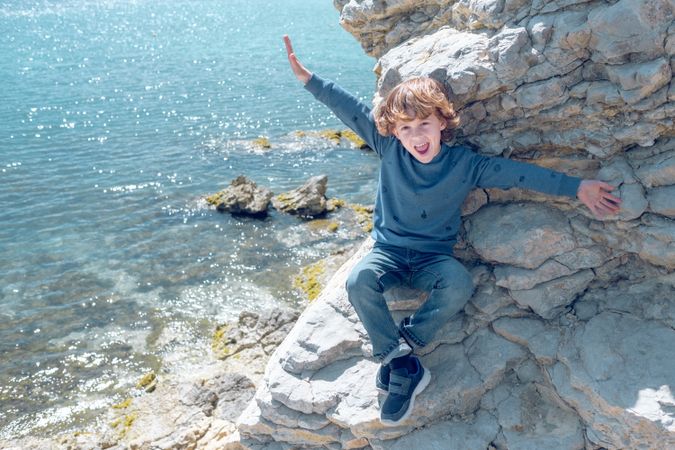 Cheerful kid on rocky cliff