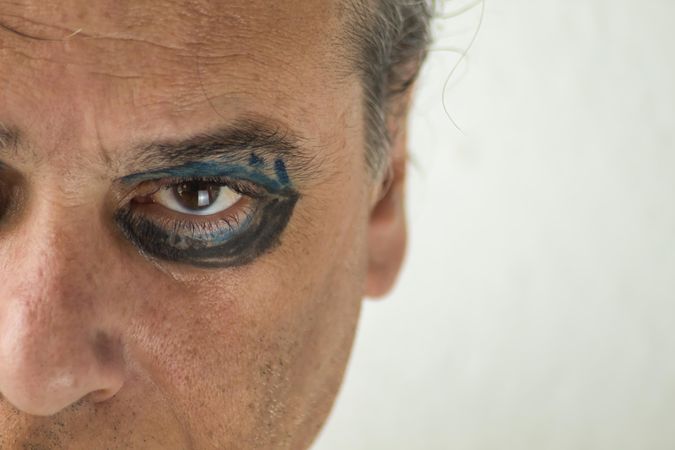 Close-up of middle aged man's left eye with dark and blue eyeshadow