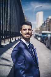 Smiling young groom near fence on street