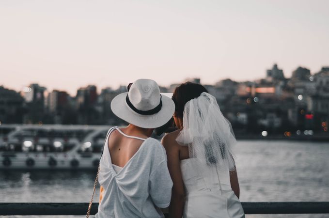 Bride and woman taking selfie near body of water