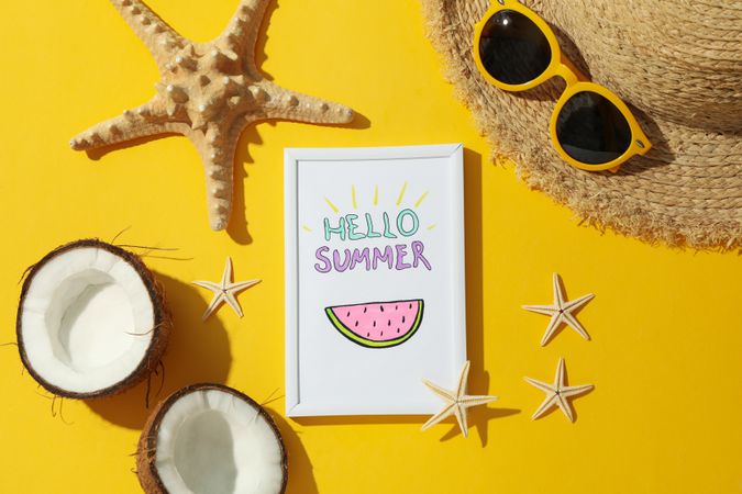 Frame with Hello summer and vacation accessories on yellow background, top view